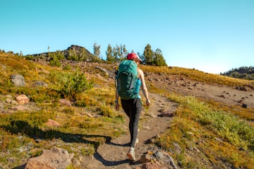 A hiker carrying a backpack on a hillside trail